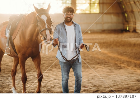 Spending time together indoors. Man is with horse in the hangar Spending time together indoors. Man is with horse in the hangar 137897187
