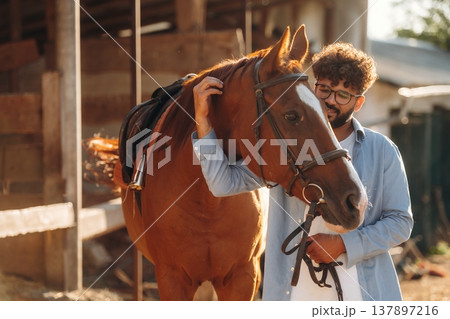 Looking at the animal. Guy is with horse on the farm 137897216