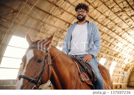 Rider is on the animal. Man is with horse in the hangar 137897236