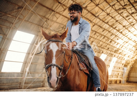Rider is on the animal. Man is with horse in the hangar Rider is on the animal. Man is with horse in the hangar 137897237