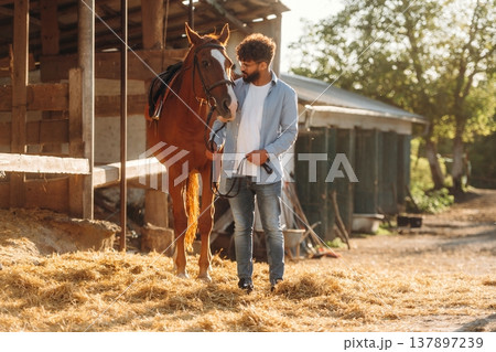 Guy is with horse on the farm Guy is with horse on the farm 137897239