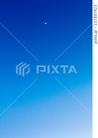 2月の澄んだ夕空に浮かぶ三日月と青のグラデーション 137897423