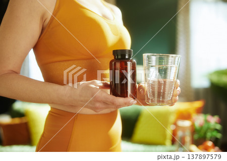Woman Holding Supplements and Water in Living Room 137897579