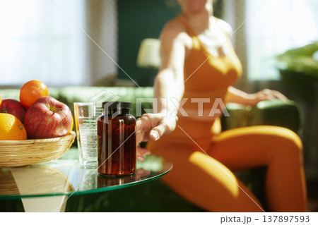Woman Reaching for Daily Vitamins and Hydration at Home Woman Reaching for Daily Vitamins and Hydration at Home 137897593