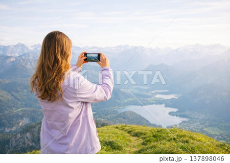 Woman taking photo of mountain landscape with smartphone during scenic travel 137898046