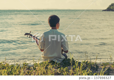 海で三線を奏でる沖縄の少年 137898327