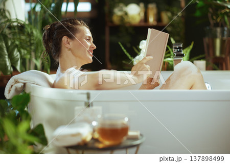 Smiling Woman Enjoying a Serene Bathtub Read 137898499