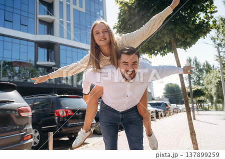 Woman is sitting on man, having fun. Happy couple together outdoors 137899259