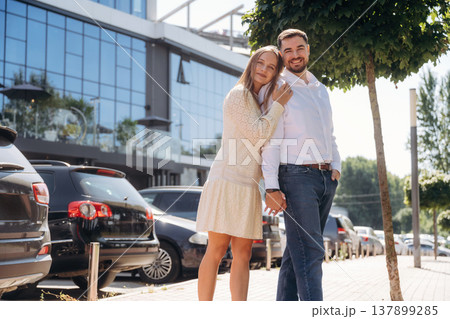 By parking lot with cars. Happy couple together outdoors By parking lot with cars. Happy couple together outdoors 137899285