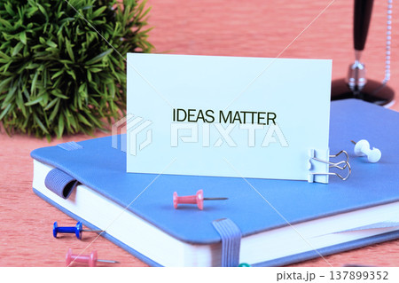 A crisp white card bearing the inspiring phrase Ideas Matter anchors a blue notebook 137899352