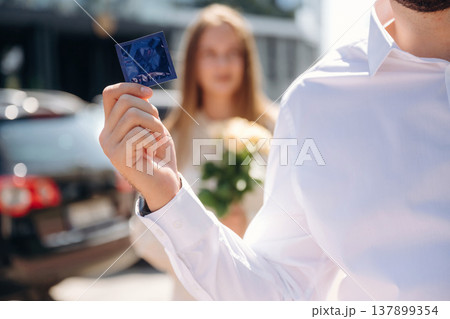 Man on a date holding condom, woman with flowers is behind 137899354