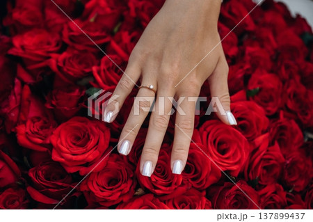 Woman got proposal, showing ring on finger over big bouquet of red flowers 137899437