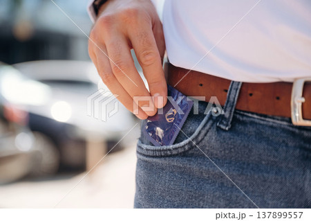 Man is putting condom in the pocket on his jeans, conception of protection Man is putting condom in the pocket on his jeans, conception of protection 137899557