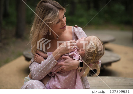 Embracing Motherhood: The tender touch of a young child nestled against her mother s shoulder illustrates the profound bond of maternal love amidst nature serenity. Embracing Motherhood: The tender touch of a young child nestled against her mother s shoulder illustrates the profound bond of maternal love amidst nature serenity. 137899621
