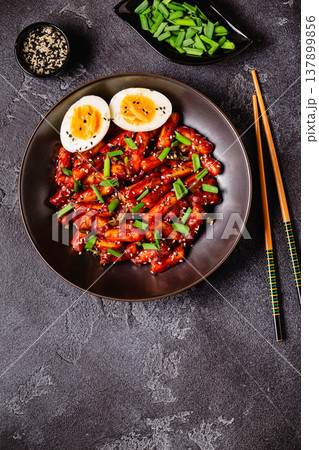 Tteokbokki, Teopokki fried rice cake in black bowl. Tteokbokki, Teopokki fried rice cake in black bowl. 137899856