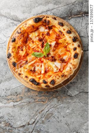 Charred pizza with smoked chicken, brie cheese and sun-dried tomatoes close-up on a wooden board. Vertical top view Charred pizza with smoked chicken, brie cheese and sun-dried tomatoes close-up on a wooden board. Vertical top view 137899877