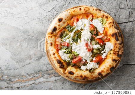 Delicious authentic pizza with stracciatella cheese, pesto, ham and cherry tomatoes close-up on a wooden board. Horizontal top view Delicious authentic pizza with stracciatella cheese, pesto, ham and cherry tomatoes close-up on a wooden board. Horizontal top view 137899885