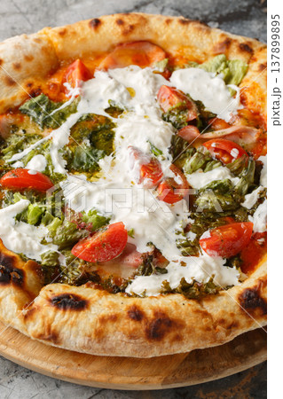 Pizza with stracciatella cheese, pesto, ham and tomatoes close-up on a wooden board. Vertical 137899895