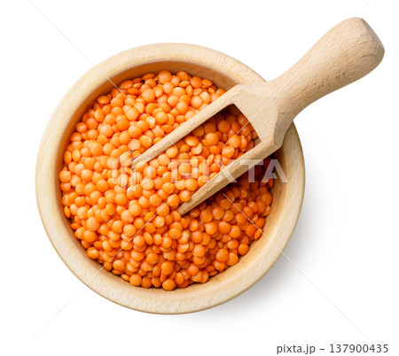 Red lentils in a wooden plate with a spatula on a white background. Top view Red lentils in a wooden plate with a spatula on a white background. Top view 137900435