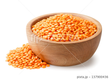 Red lentils in a wooden plate and a pile on a white background. Isolated 137900436