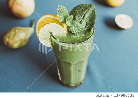 A healthy green smoothie made with fresh spinach, standing on a table with a turquoise tablecloth 137900539