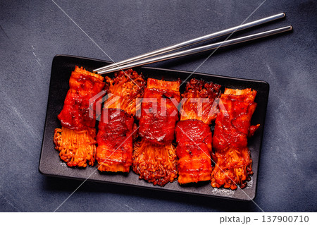 Bacon roll with enoki mushroom grilled with sauce. 137900710