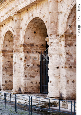 Old stone wall with holes near metal gate in historic city area Old stone wall with holes near metal gate in historic city area 137901065