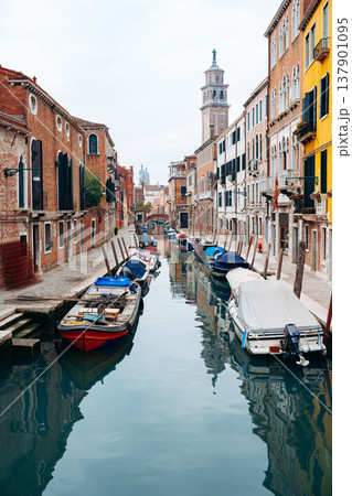 Boats docked in a canal next to buildings in Venice during a cloudy day 137901095