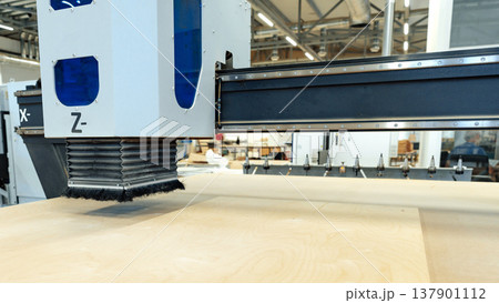 CNC machine cutting wood in a workshop during the day CNC machine cutting wood in a workshop during the day 137901112