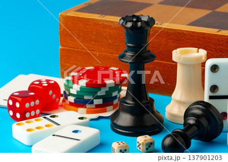 Board games and playing pieces on a blue surface with a wooden game box in view 137901203