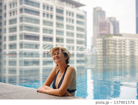Young woman relaxing by the pool at a Kuala Lumpur hotel Young woman relaxing by the pool at a Kuala Lumpur hotel 137901578