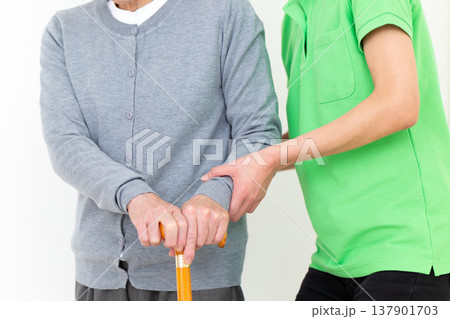足が悪いお年寄りを介助する介護福祉士 137901703