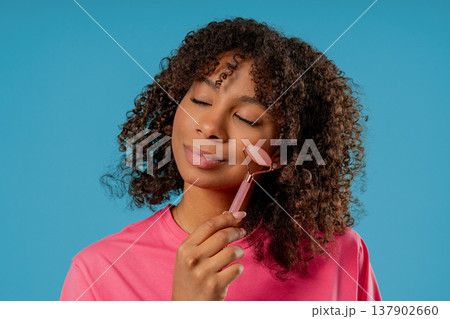 Charming African Woman Doing Face Massage With Rose Quartz Stone Roller Firmer 137902660