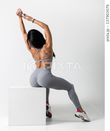 Athletic woman posing in gray sports bra leggings on a white studio background Athletic woman posing in gray sports bra leggings on a white studio background 137903076