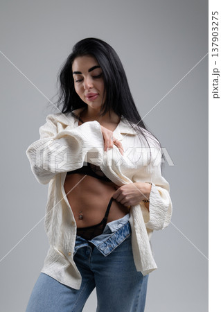 Attractive woman undressing, wearing lingerie and jeans, white studio background 137903275