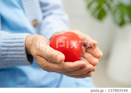 Asian elder senior woman patient holding red heart in hospital. Asian elder senior woman patient holding red heart in hospital. 137903549