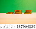 Stacks of golden coins on green background symbolizing financial growth, savings, investment and wealth with copy space. 137904329