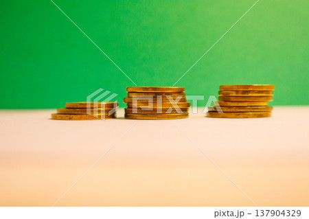 Stacks of golden coins on green background symbolizing financial growth, savings, investment and wealth with copy space. 137904329