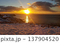 A stunning sunrise casts golden light over a snowy coastline in the Kuril Islands. 137904520