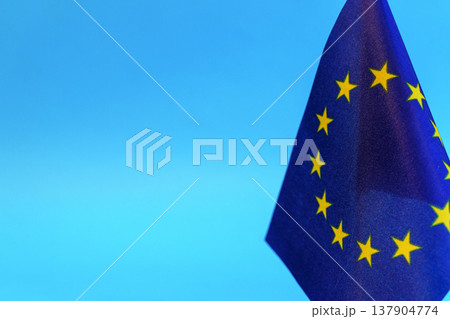 Flag European Union against a blue background symbolizing unity and political cooperation. Close-up view of the EU flag representing European integration, international diplomacy, and regional Flag European Union against a blue background symbolizing unity and political cooperation. Close-up view of the EU flag representing European integration, international diplomacy, and regional 137904774
