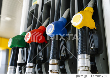 Fuel pump nozzles hanging at a modern gas station during a period of high oil prices. A conceptual photography showcasing the global energy crisis, increasing gasoline costs Fuel pump nozzles hanging at a modern gas station during a period of high oil prices. A conceptual photography showcasing the global energy crisis, increasing gasoline costs 137904780