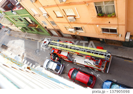 Fire Truck Arrives to Respond to an Emergency in a Narrow Street Lined With Buildings in a City During Daytime 137905098