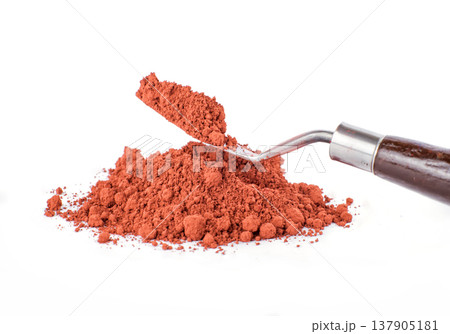 Bright Orange pigment Spice Spilling From Container With Scoop on White Background 137905181