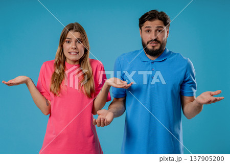 Confused young couple shrugging shoulders in uncertainty while looking at camera 137905200