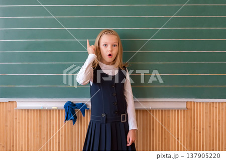 First grade pupil a girl writing on green blackboard at school lesson First grade pupil a girl writing on green blackboard at school lesson 137905220