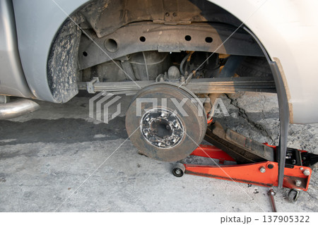 The side view shows the jack and tools used to lift the vehicle and remove the wheel. 137905322