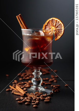 Iced coffee garnished with a cinnamon stick and a dried orange slice. Iced coffee garnished with a cinnamon stick and a dried orange slice. 137905391