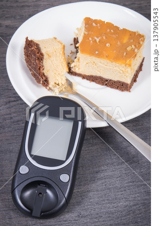 Glucometer and sweet cheesecake. Measuring and sugar level control during diabetes Glucometer and sweet cheesecake. Measuring and sugar level control during diabetes 137905543