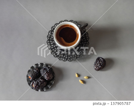 Top view a cup of dark coffee sits on ornate metal coaster. Top view a cup of dark coffee sits on ornate metal coaster. 137905787