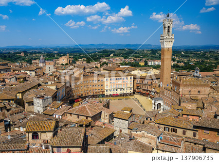 A panoramic view over Piazza del Campo, the heart of Siena, surrounded by medieval buildings and dominated by the Torre del Mangia. 137906735
